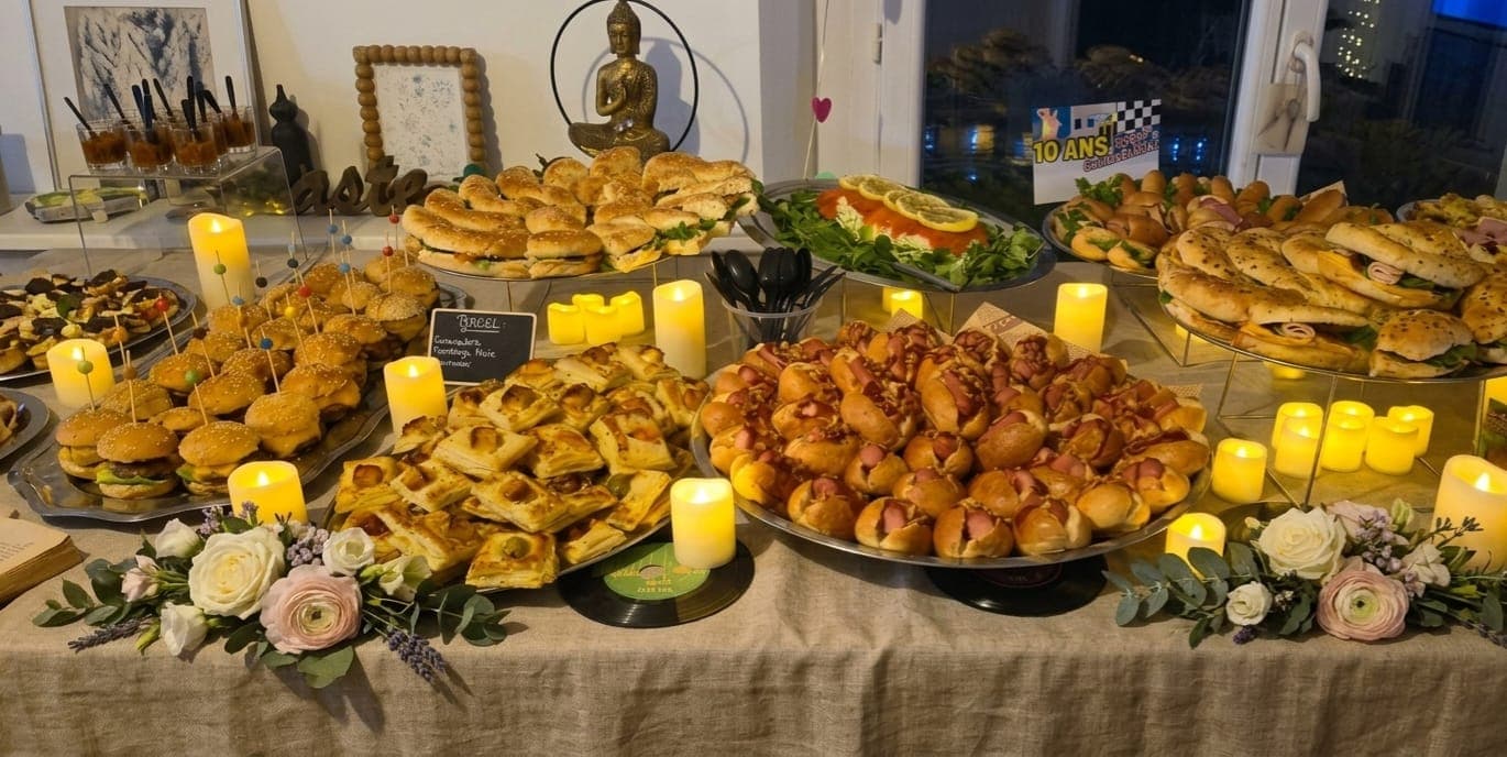 Buffet couvert de plateaux salés, de bougies et de fleurs sur une nappe en lin