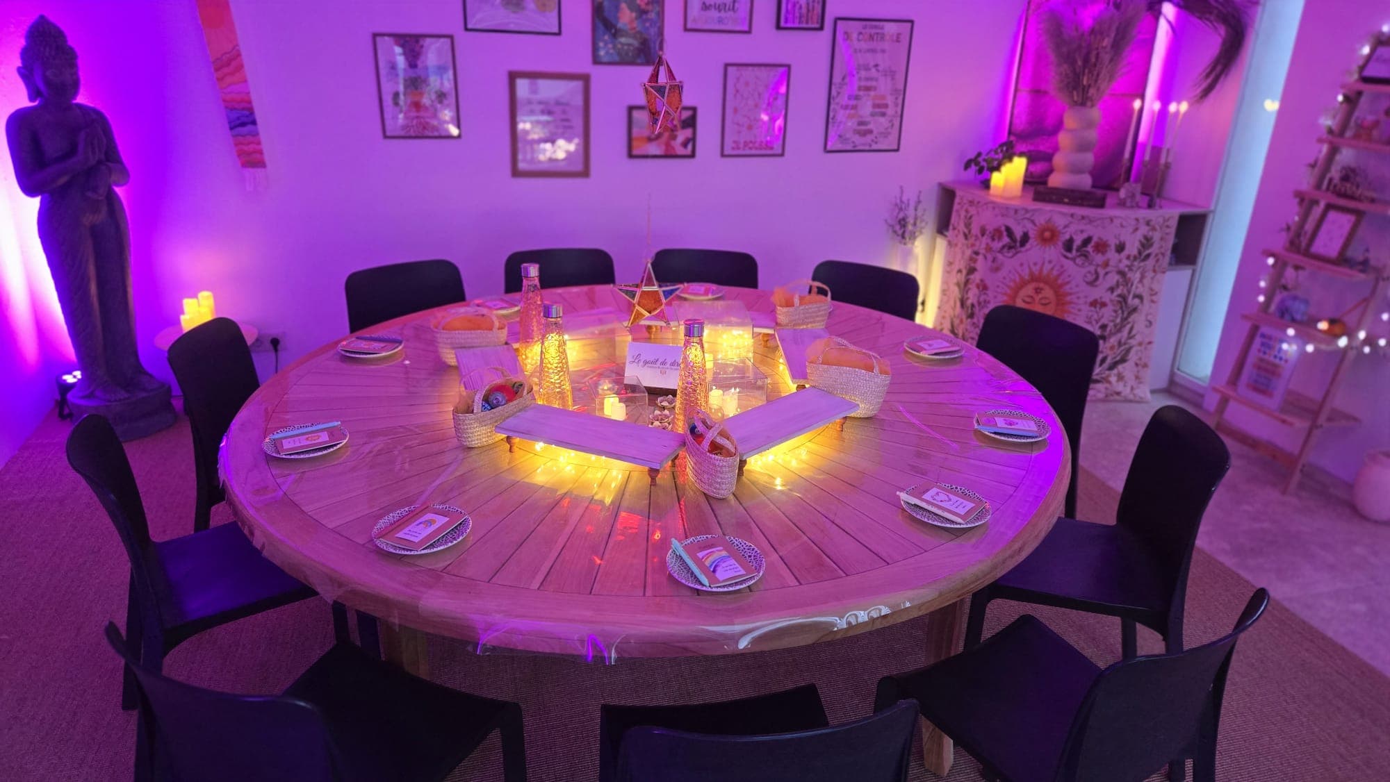 Table ronde dressée et bougies allumées au centre, avant l'arrivée des participants