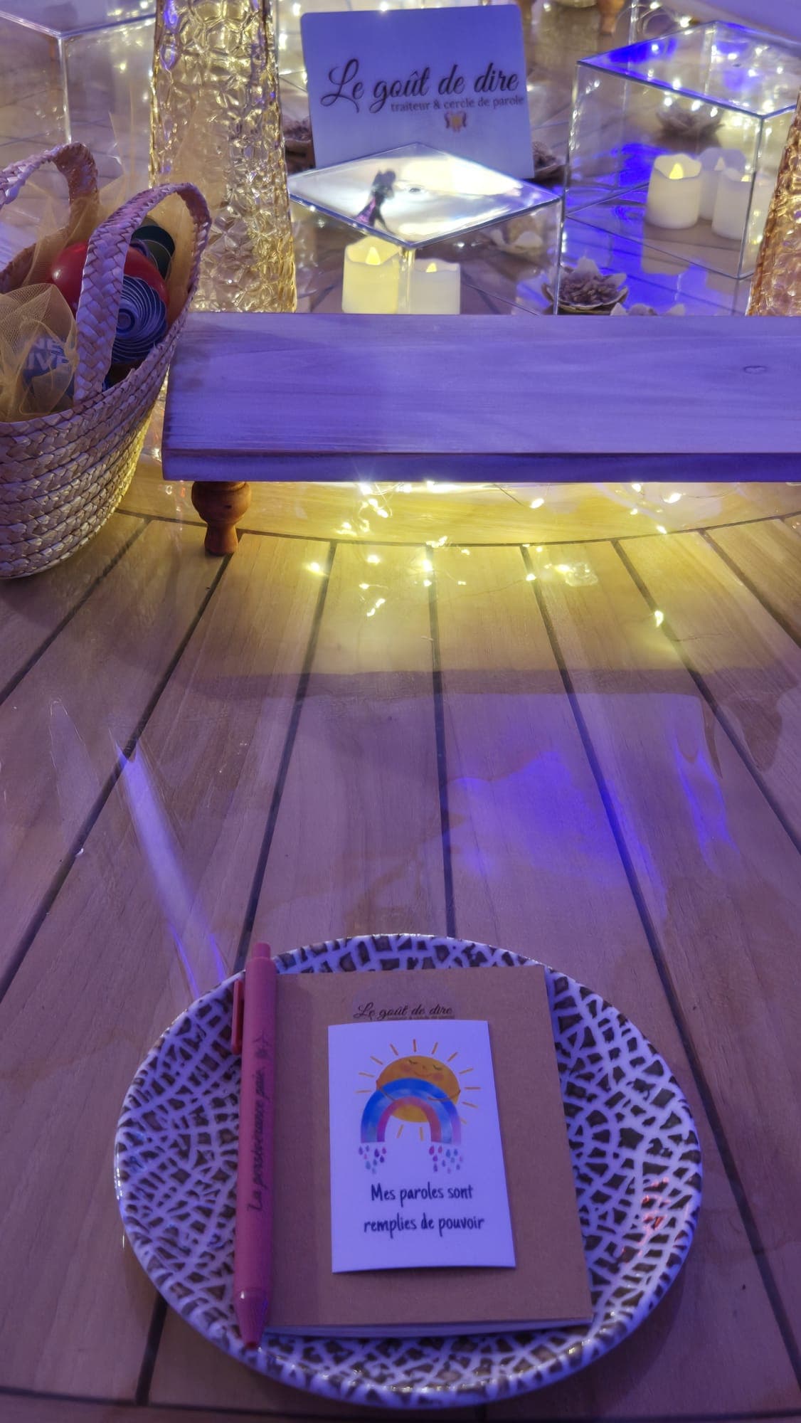 Terrasse en bois éclairée de guirlandes lumineuses, avec un banc et un panier en osier